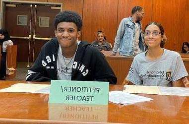 Two EOP students sitting at table for mock trial in court room.