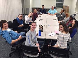 Students sitting around a table smiling