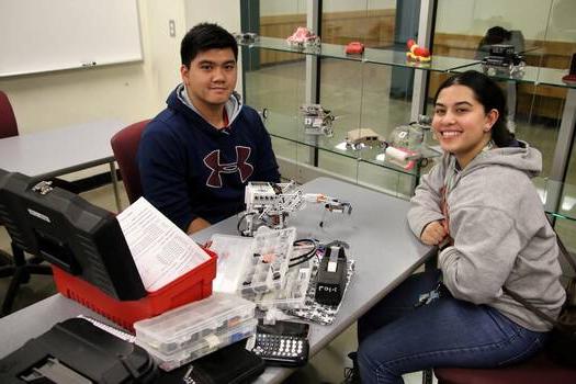 Floor-to-ceiling glass wall allows a view of students working on engineering projects, utilizing updated resources.