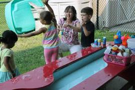 child care center kids playing at a water table outside